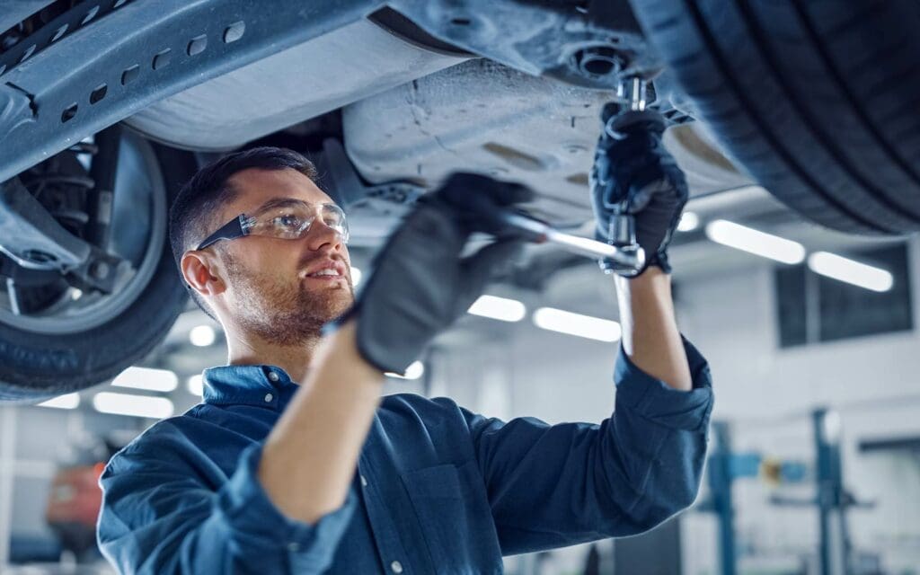 Repair technician working on the underside of a vehicle