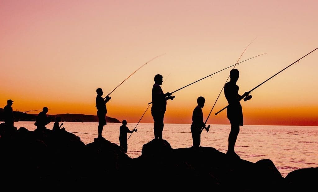 Several fishers on the beach at sunset