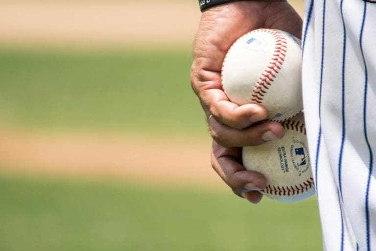 A close of a baseball pitcher holding two balls in his left hand