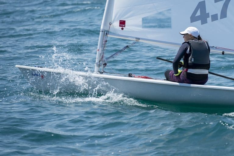 A close-up of a person steering a sailboat in a regatta.